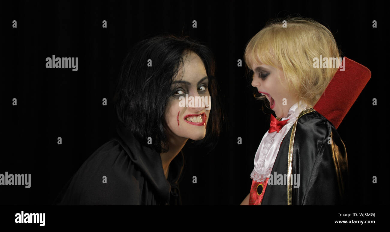 Woman and child dracula making faces. Little girl with her mother. Halloween make-up. Vampire kid with blood on her face. Happy Halloween holiday horror concept. Friday 13th theme Stock Photo