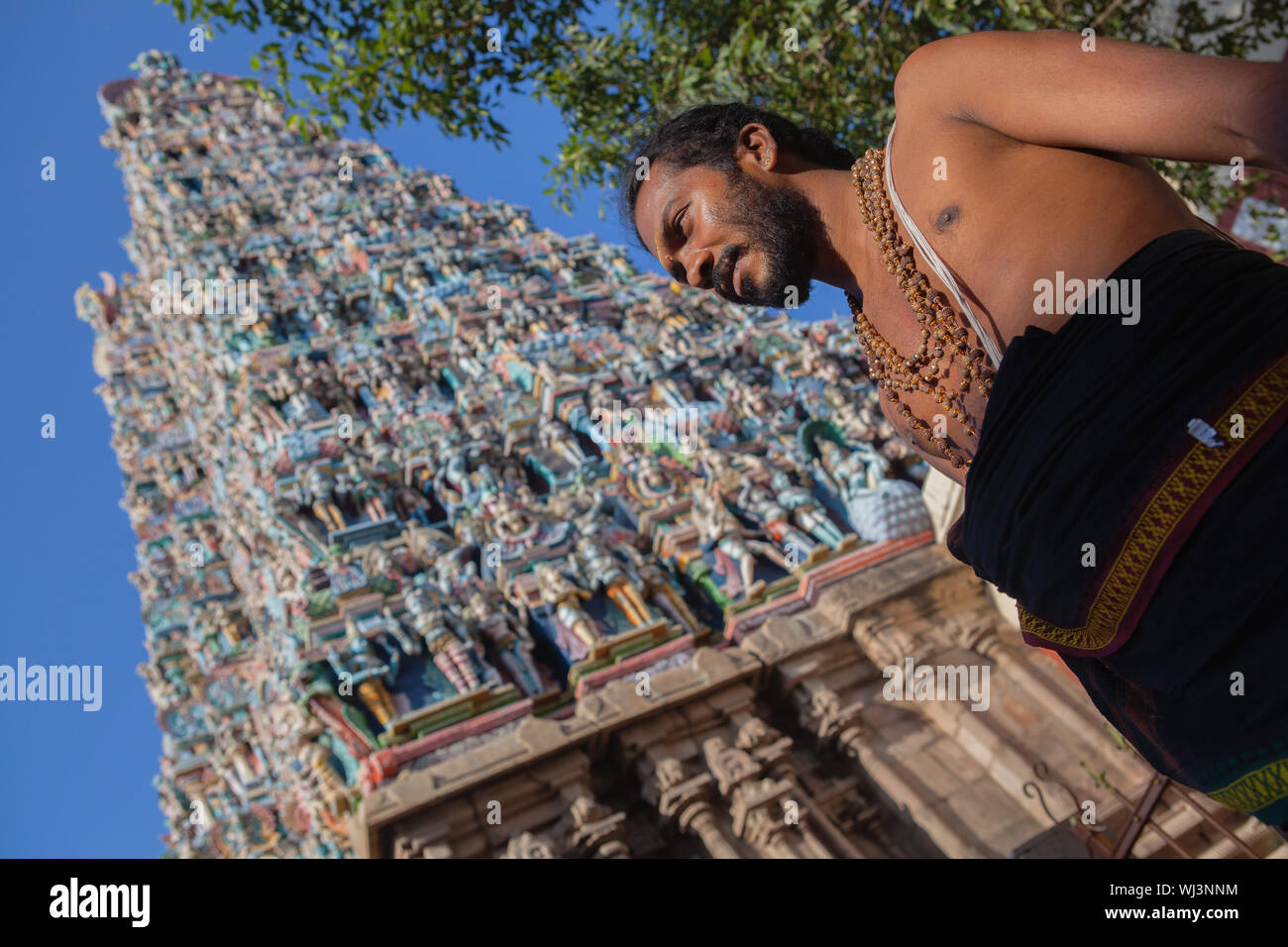 India, Tamil Nadu, Madurai, Pilgrim in front of the west tower gopuram of the Sri Meenakshi Temple in Madurai. Stock Photo