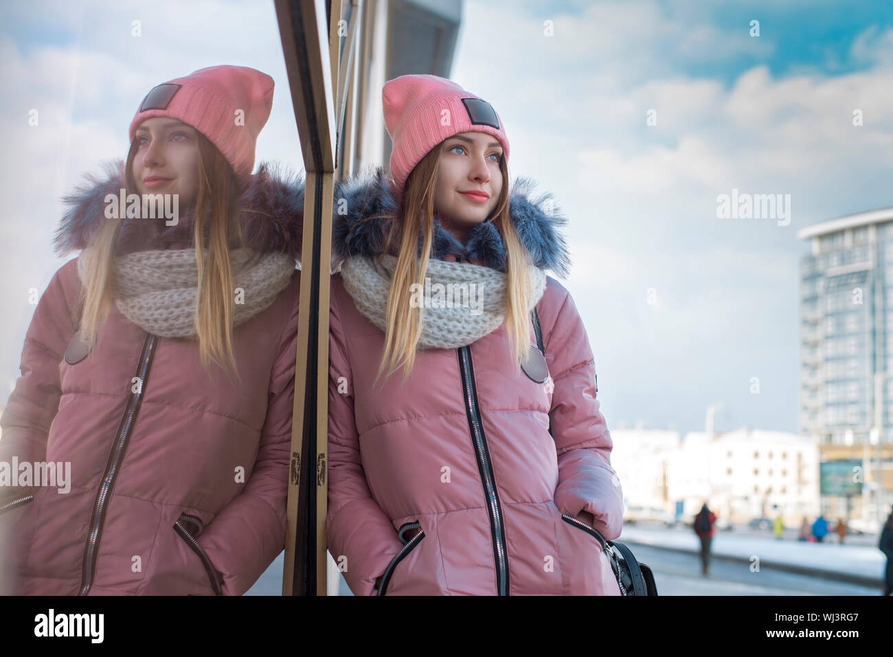 A girl in a pink jacket walks in the winter in the city Stock Photo