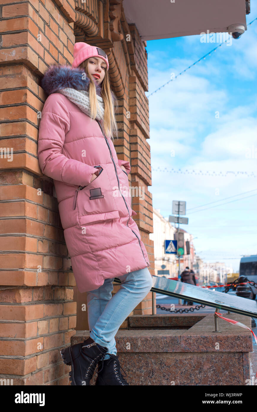 A girl in a pink jacket walks in the winter in the city Stock Photo