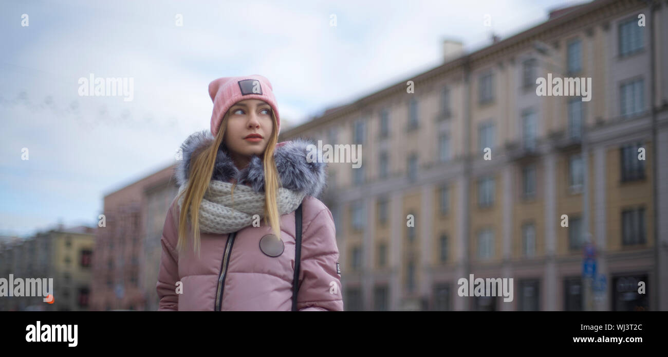 A girl in a pink jacket walks in the winter in the city Stock Photo
