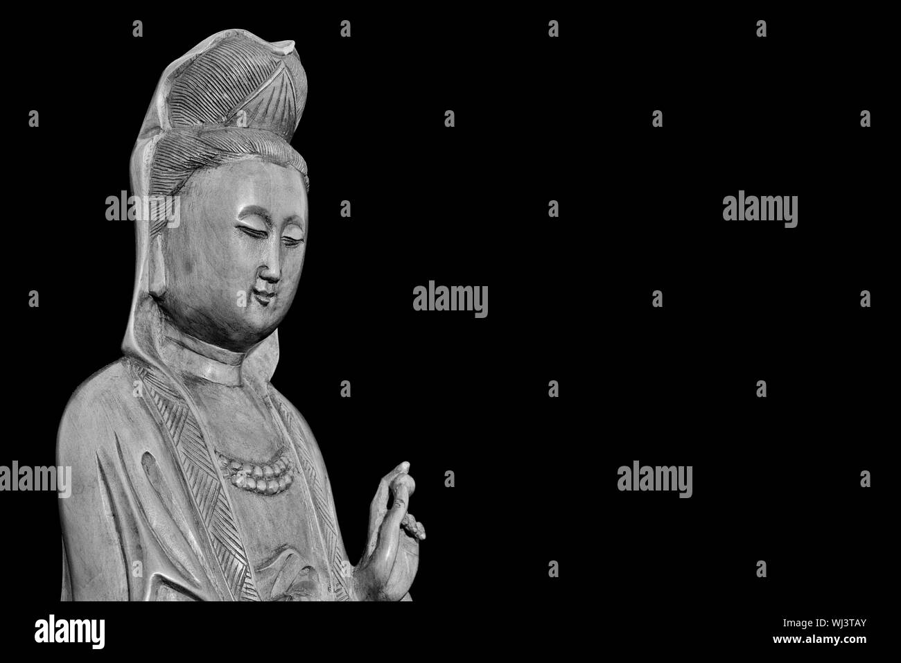 Buddhist religion and meditation. Kannon or Guanyin, the Goddess of Mercy, wooden statuette (Black adn White with copy space) Stock Photo