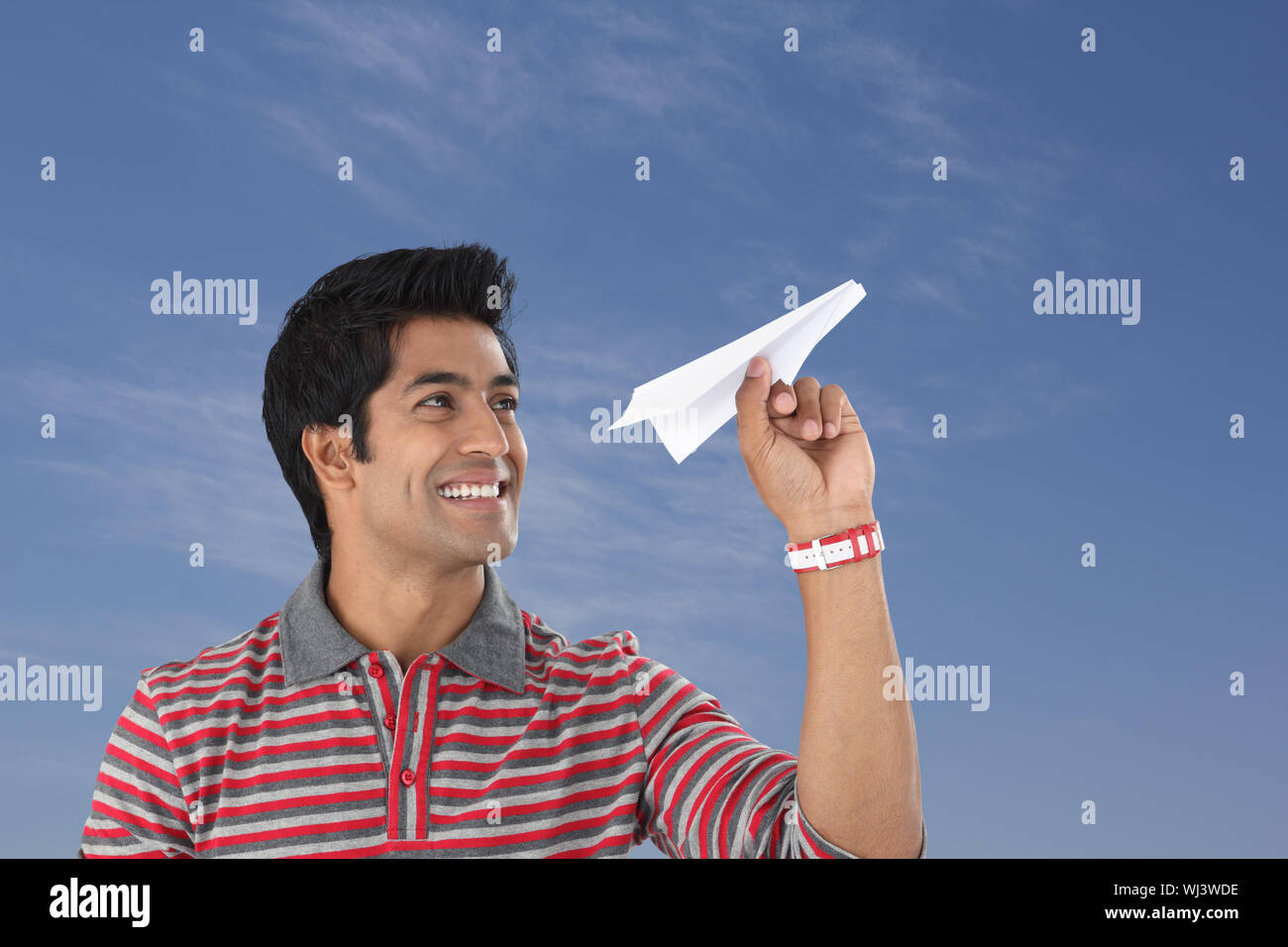 Young man throwing a paper airplane and smiling Stock Photo