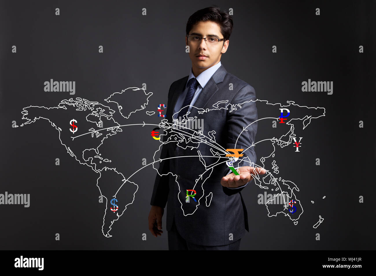 Businessman holding currency symbols on a touch screen representing countries in a world map Stock Photo