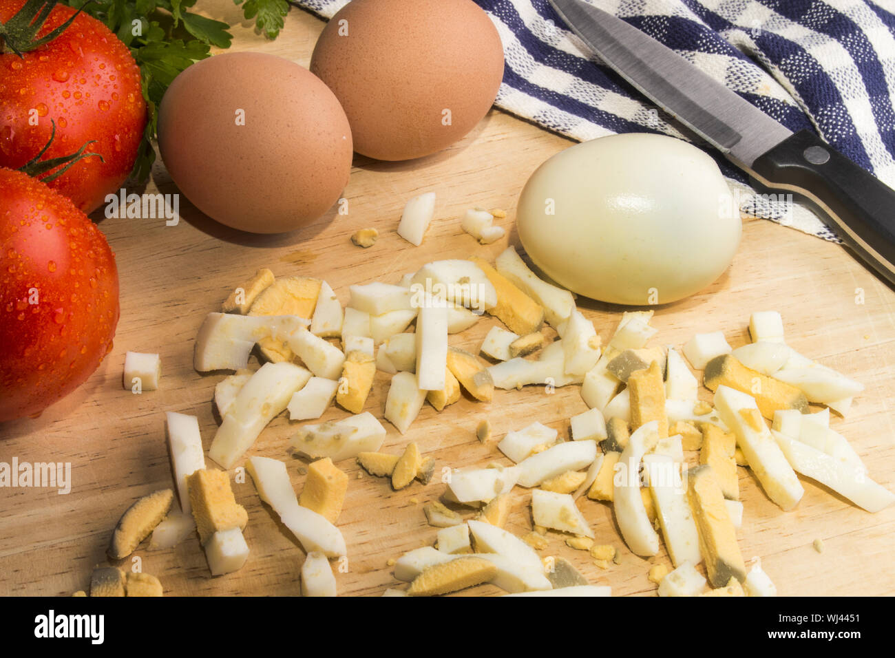wet tomatoes, diced boiled eggs on a wooden board Stock Photo