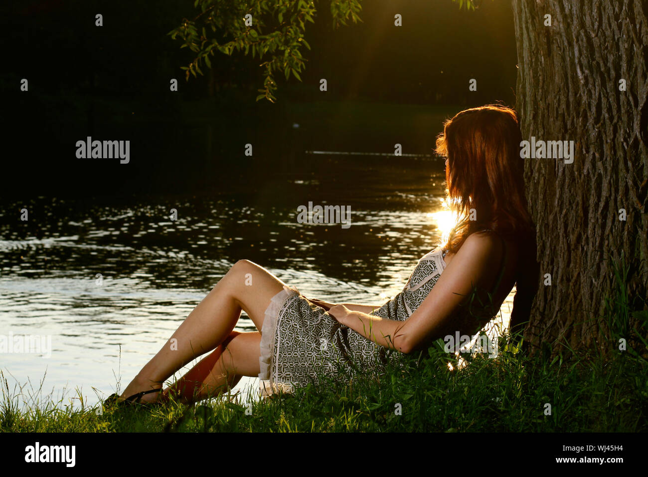 Girl sitting on tha bank of forest river Stock Photo - Alamy