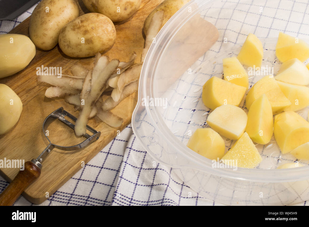 peeled and cut potatoes on a wooden board ready to boil in a steamer Stock Photo