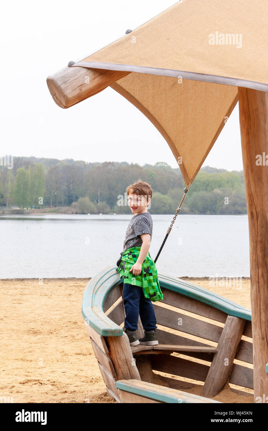 A young boy standing at the front of a play ship on the beach at Ruislip Lido, Greater London Stock Photo