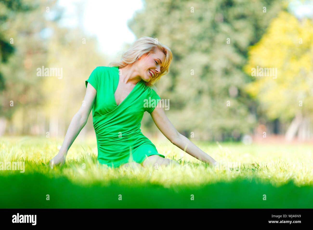Happy young woman sitting on grass Stock Photo - Alamy