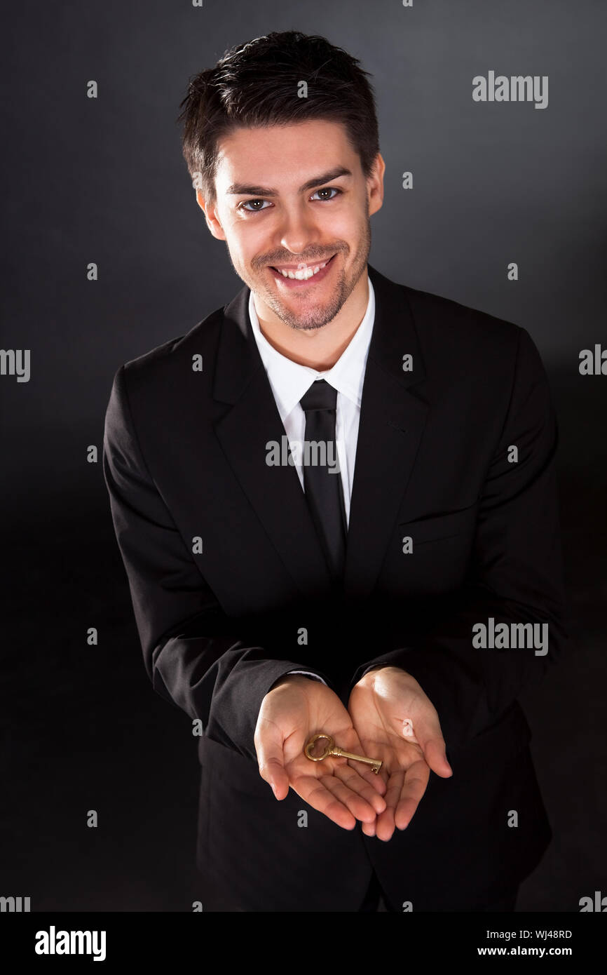 Smiling young businessman holding up a golden key in his hand Stock ...