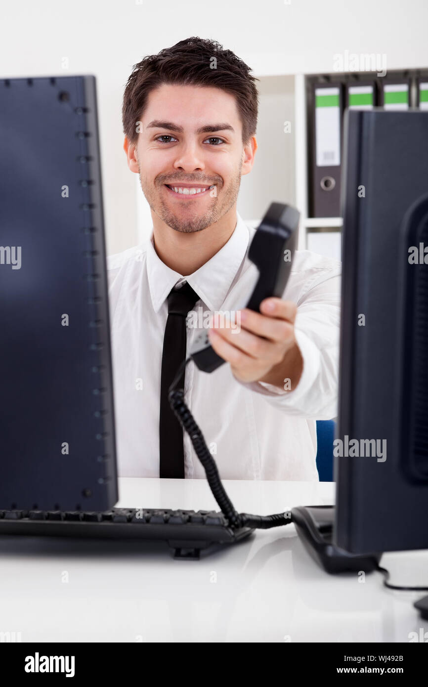 View Between Two Computer Monitors Of A Handsome Smiling Stock Broker