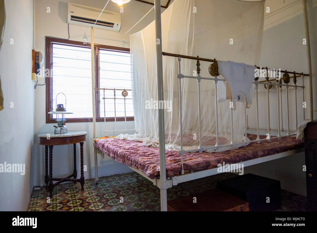 A white bedroom with a brass bed at the Hakka Tin Miners Club Museum