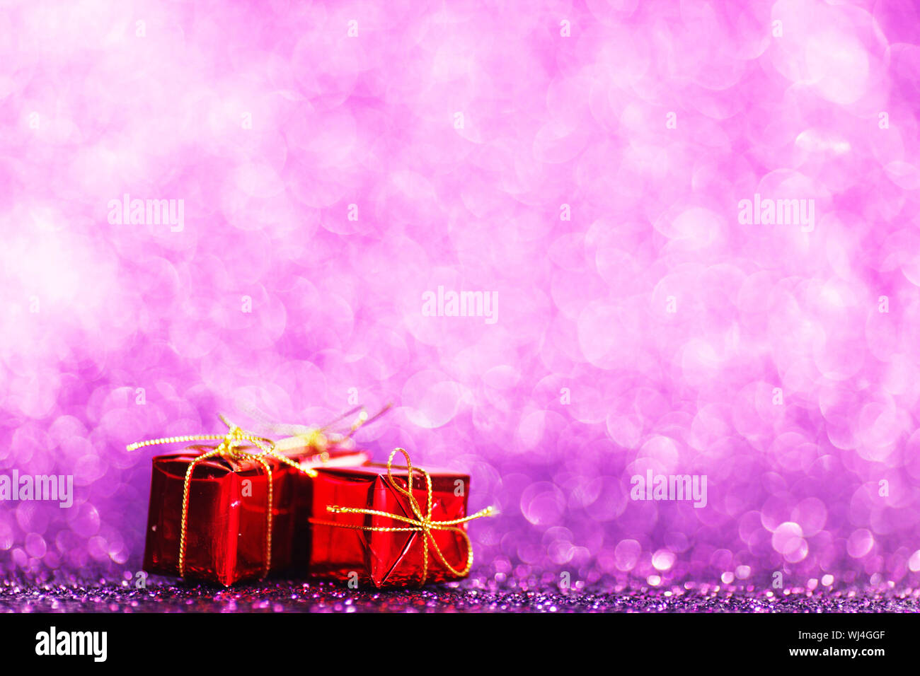 Red Christmas gift boxes on shiny glitter purple background Stock Photo