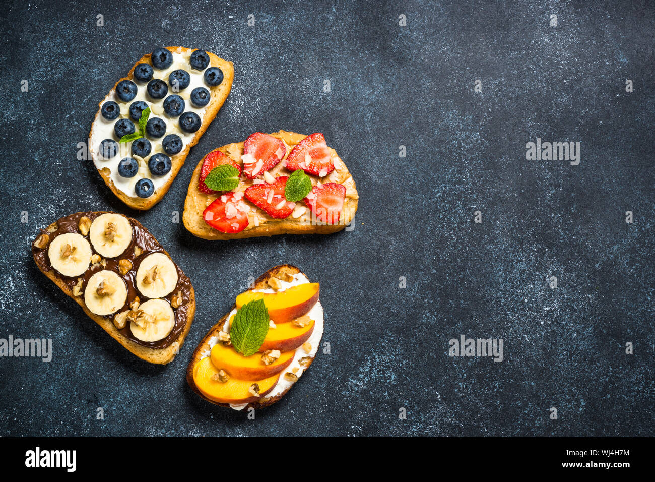 Sweet toast assortment with fresh fruit and berries on black. Stock Photo