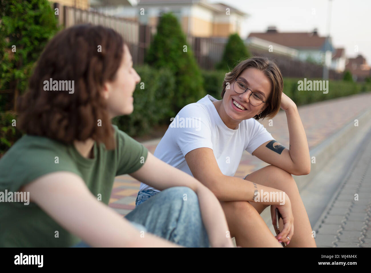 Women friends talking on neighborhood curb Stock Photo