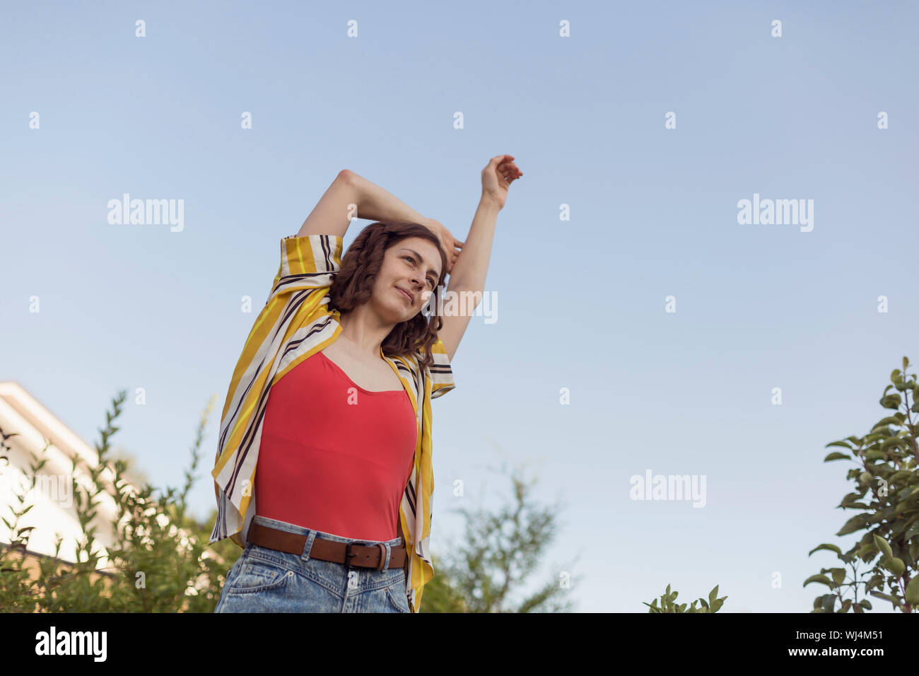 Carefree woman stretching arm overhead Stock Photo