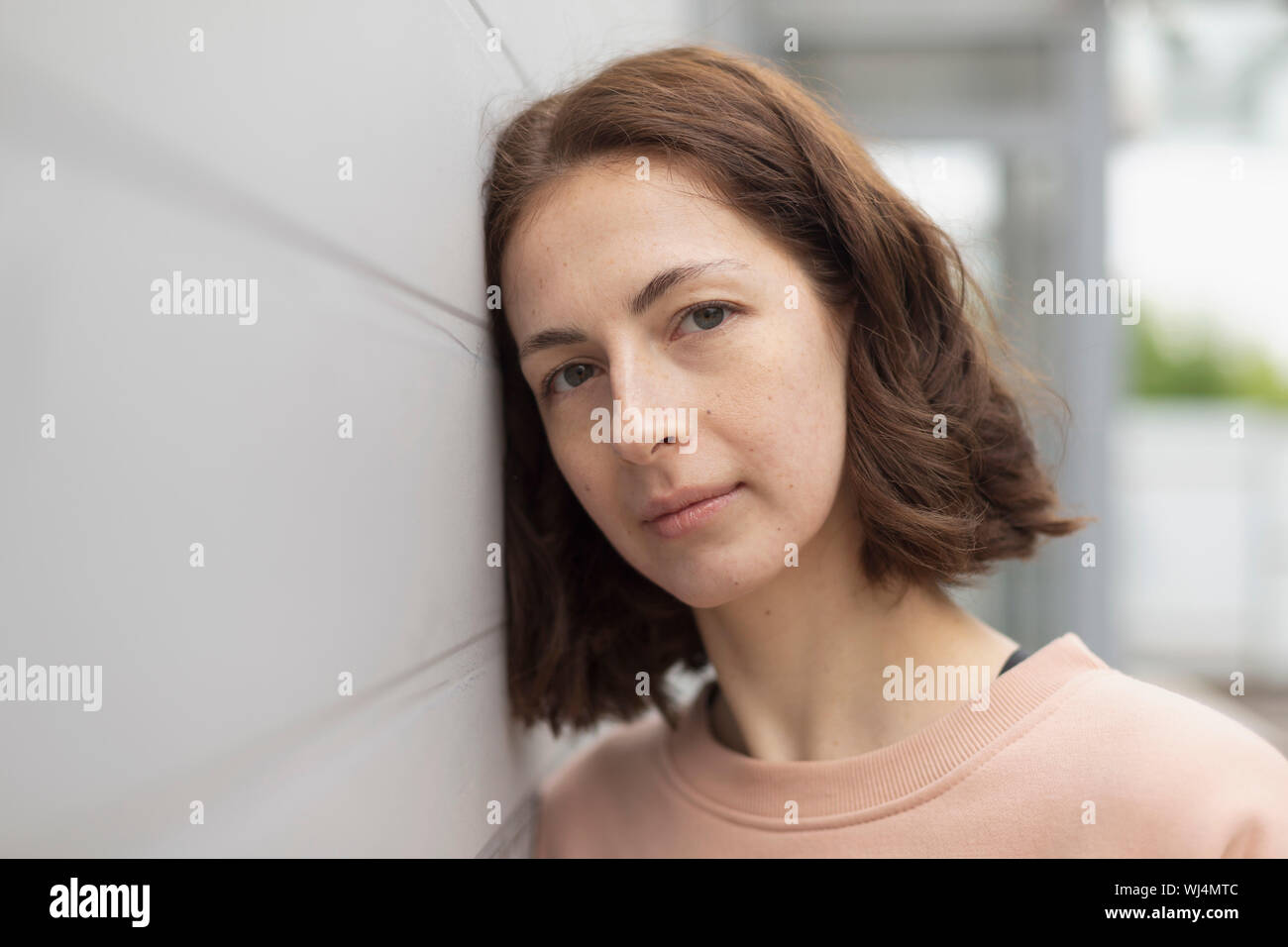 Portrait serene woman leaning against wall Stock Photo