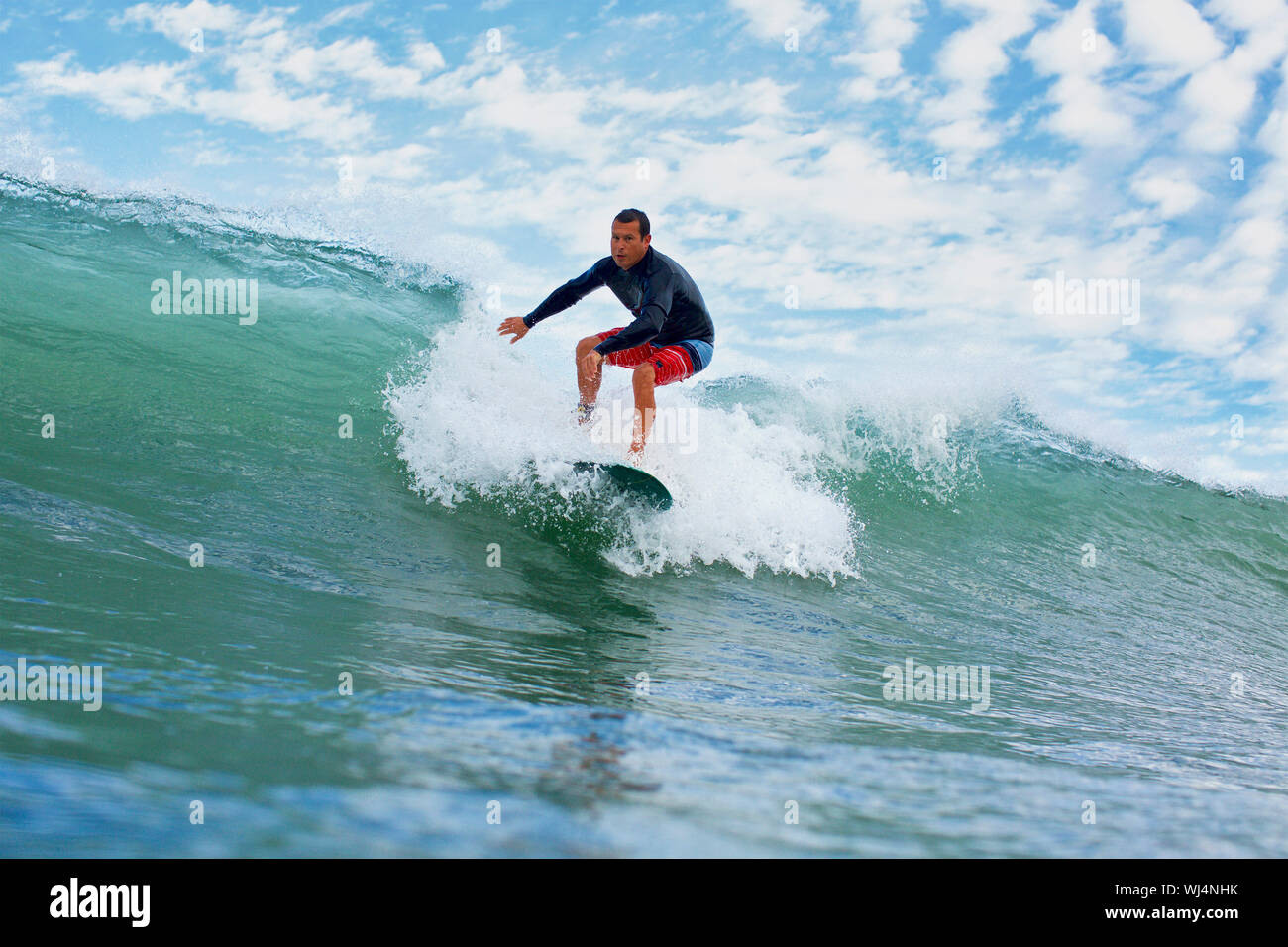 Male surfer riding ocean wave Stock Photo