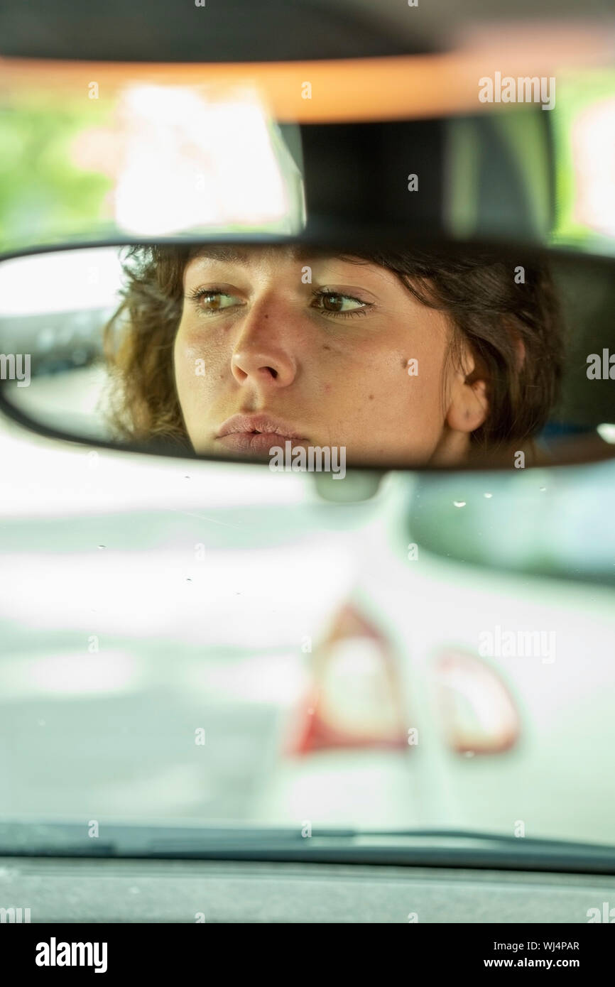 Reflection of woman in rear-view mirror driving car Stock Photo