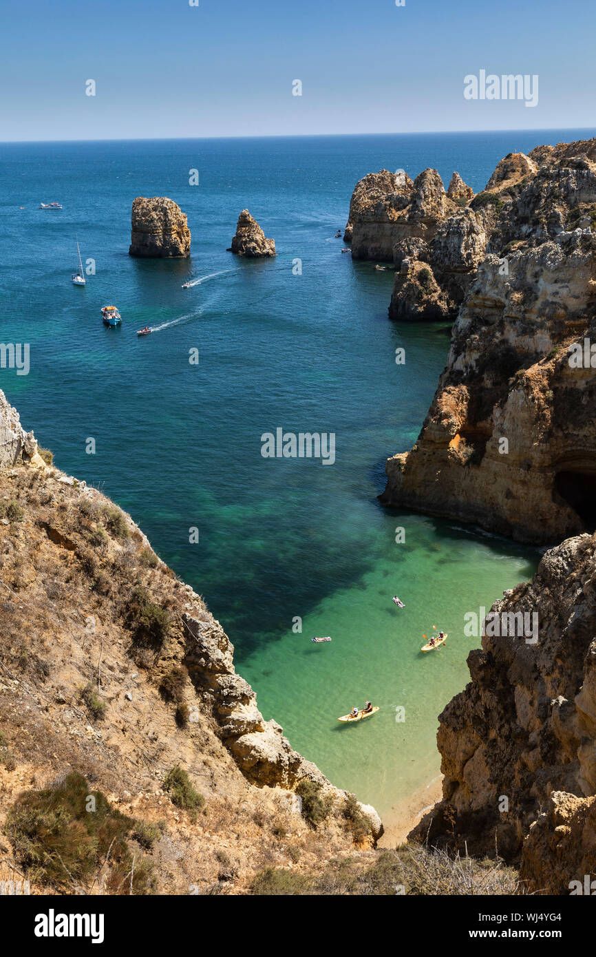 Aerial view tourists boating along ocean cliffs, Lagos, Algarve, Portugal Stock Photo
