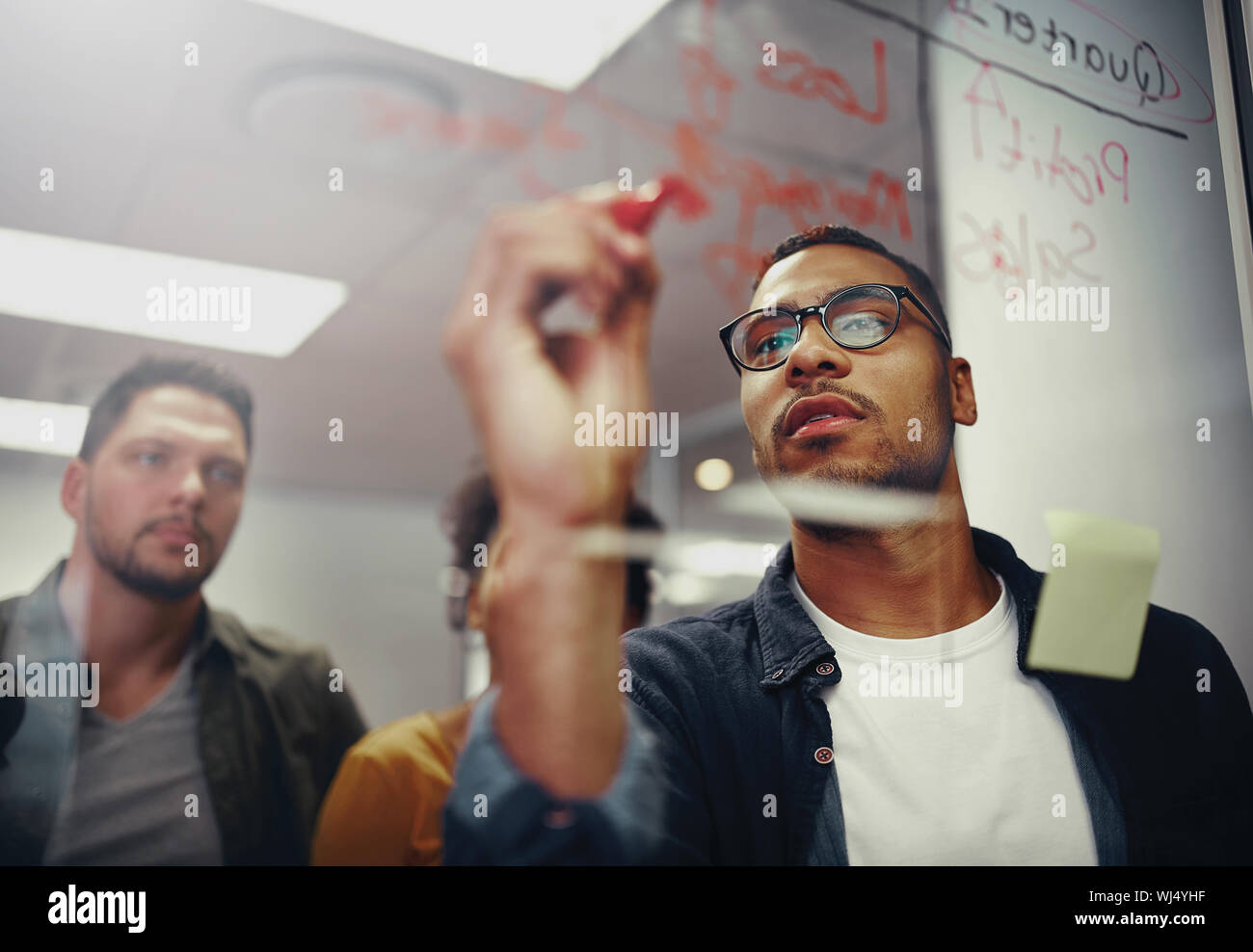 Young creative startup business people in meeting at modern office making plans on transparent glass Stock Photo