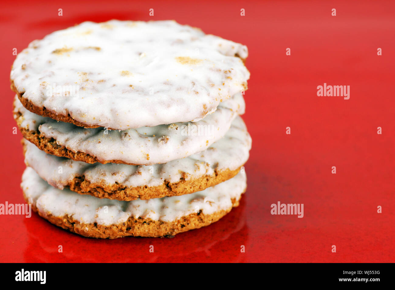 Pile of oatmeal cookies with sugar icing on red plate background Stock Photo