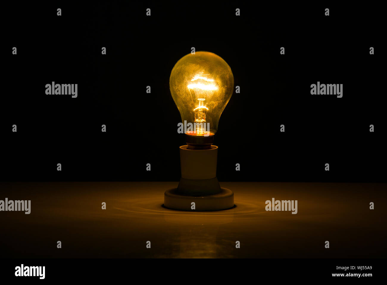 Illuminated light bulb in dark room Stock Photo