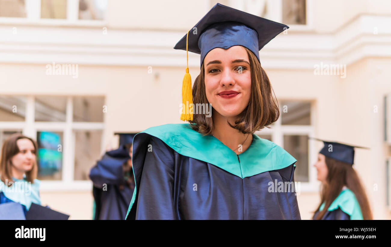 A group of young female graduates. Female graduate is smiling against the background of university graduates. Concept of education, graduation and kno Stock Photo
