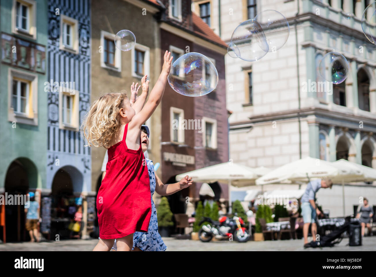 Girls chasing and popping giant bubbles. Stock Photo