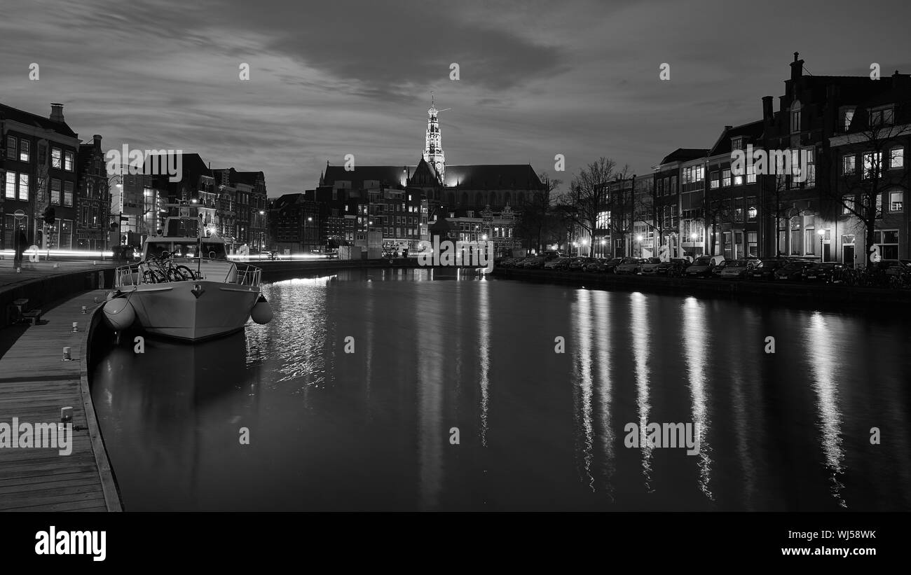 Illuminated Grote Kerk With Reflection In Spaarne River Against Sky At Night Stock Photo