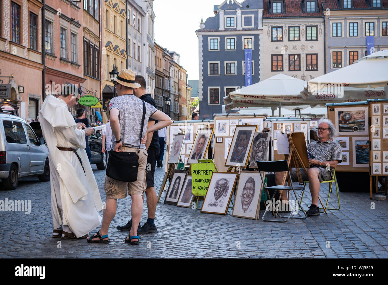 Tourists and artist in Warsaw Old Town Square market. Stock Photo