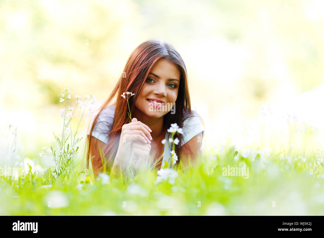 Beautiful young woman lying on grass with flowers Stock Photo - Alamy