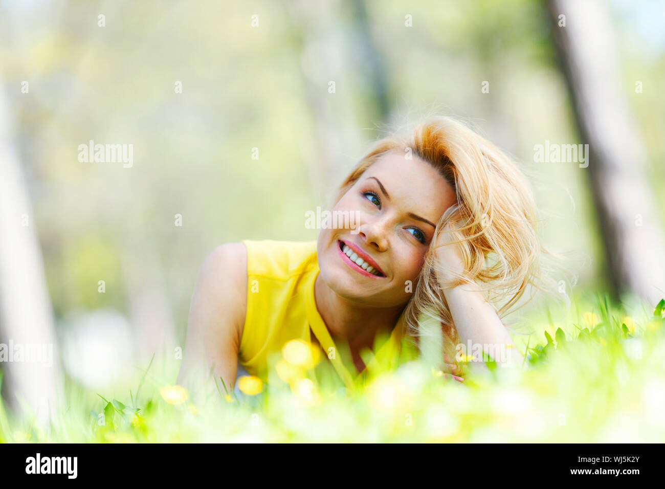 Happy young woman lying on grass Stock Photo - Alamy
