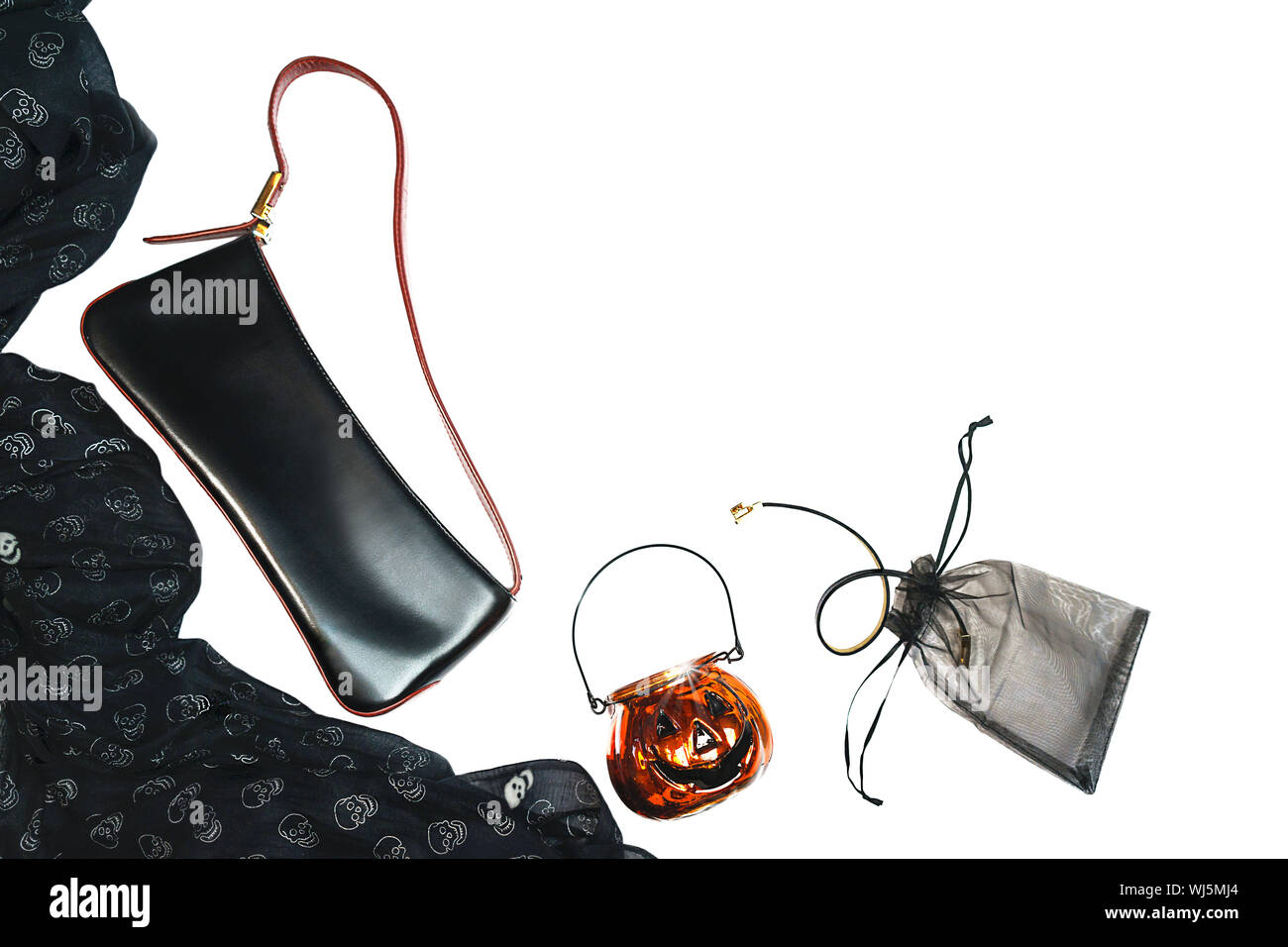 Halloween party female outfit layout of accessories black on white background: shoes, handbag, cloth with skulls, jewelry and glass pumpkin. Stock Photo