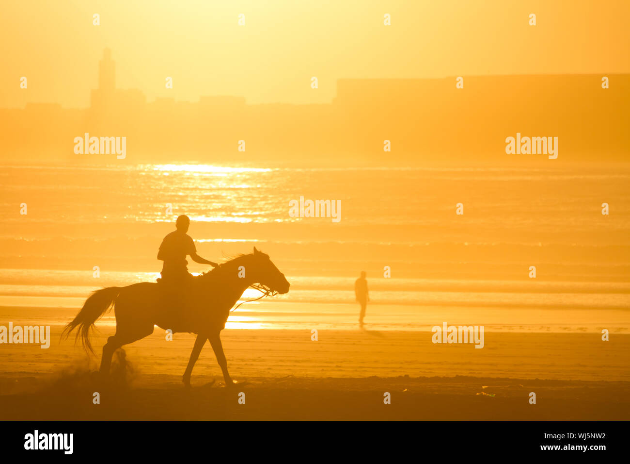 Man riding horse on the beach at sunset Stock Photo - Alamy