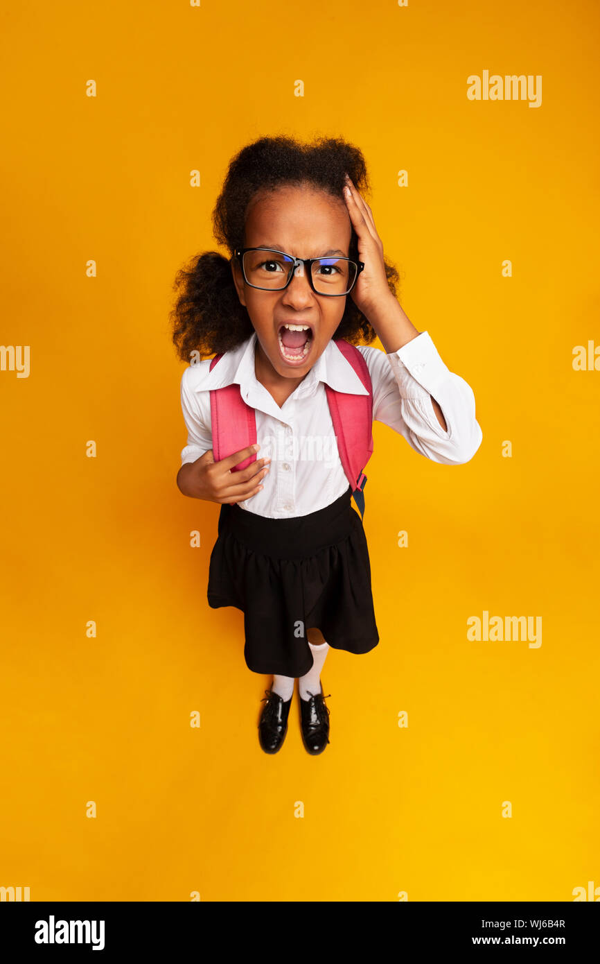 Little School Girl Shouting Touching Head On Yellow Background Stock Photo