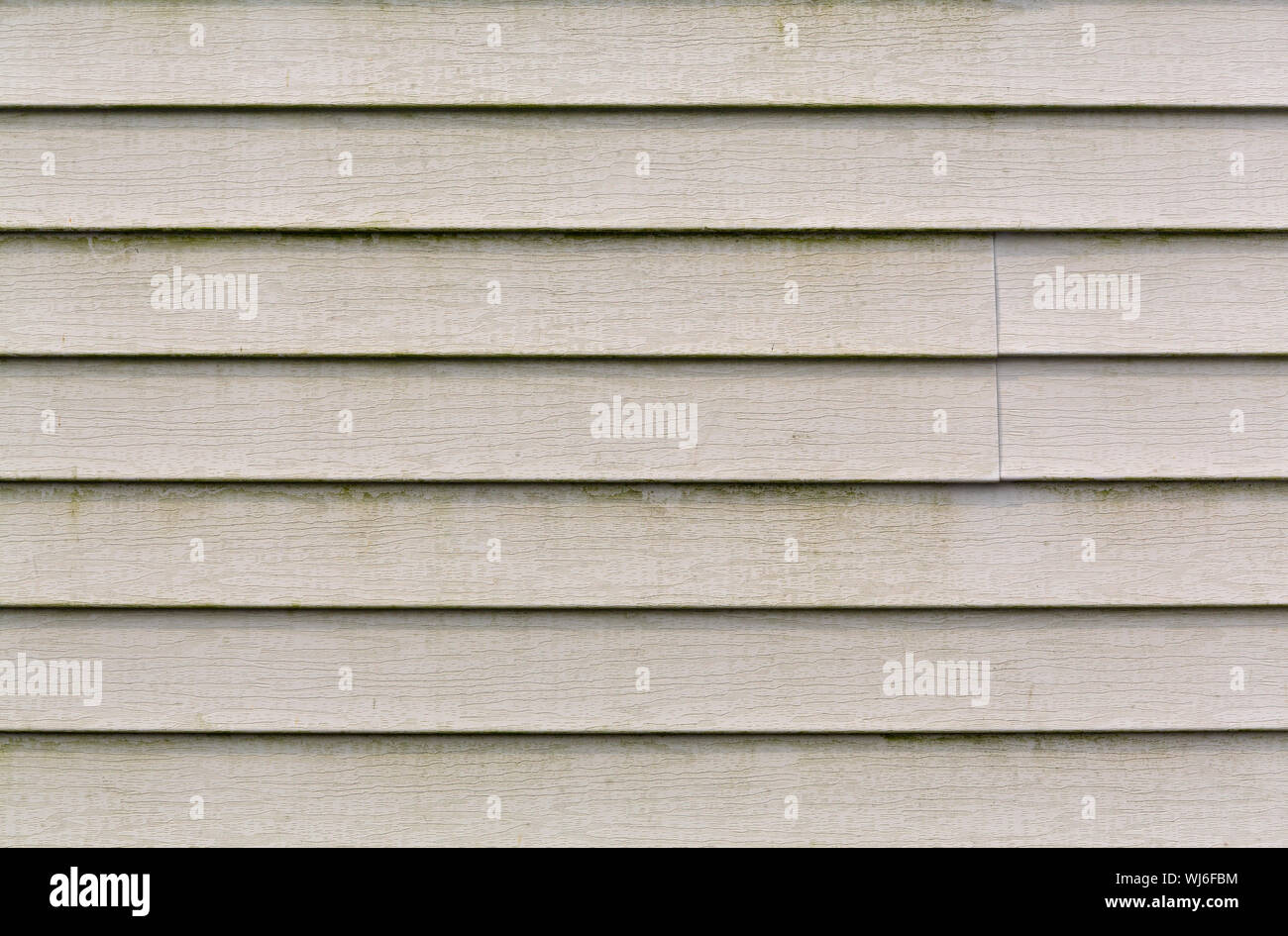 Wide view of several rows of beige vinyl siding with a large amount of