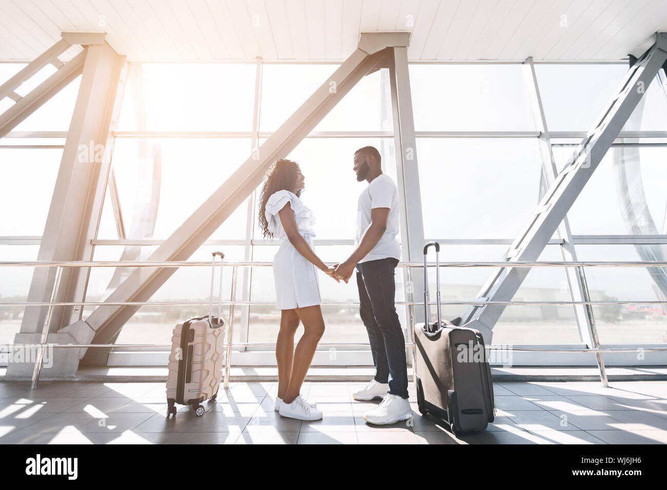 Millennial african couple holding hands at airport terminal Stock Photo ...