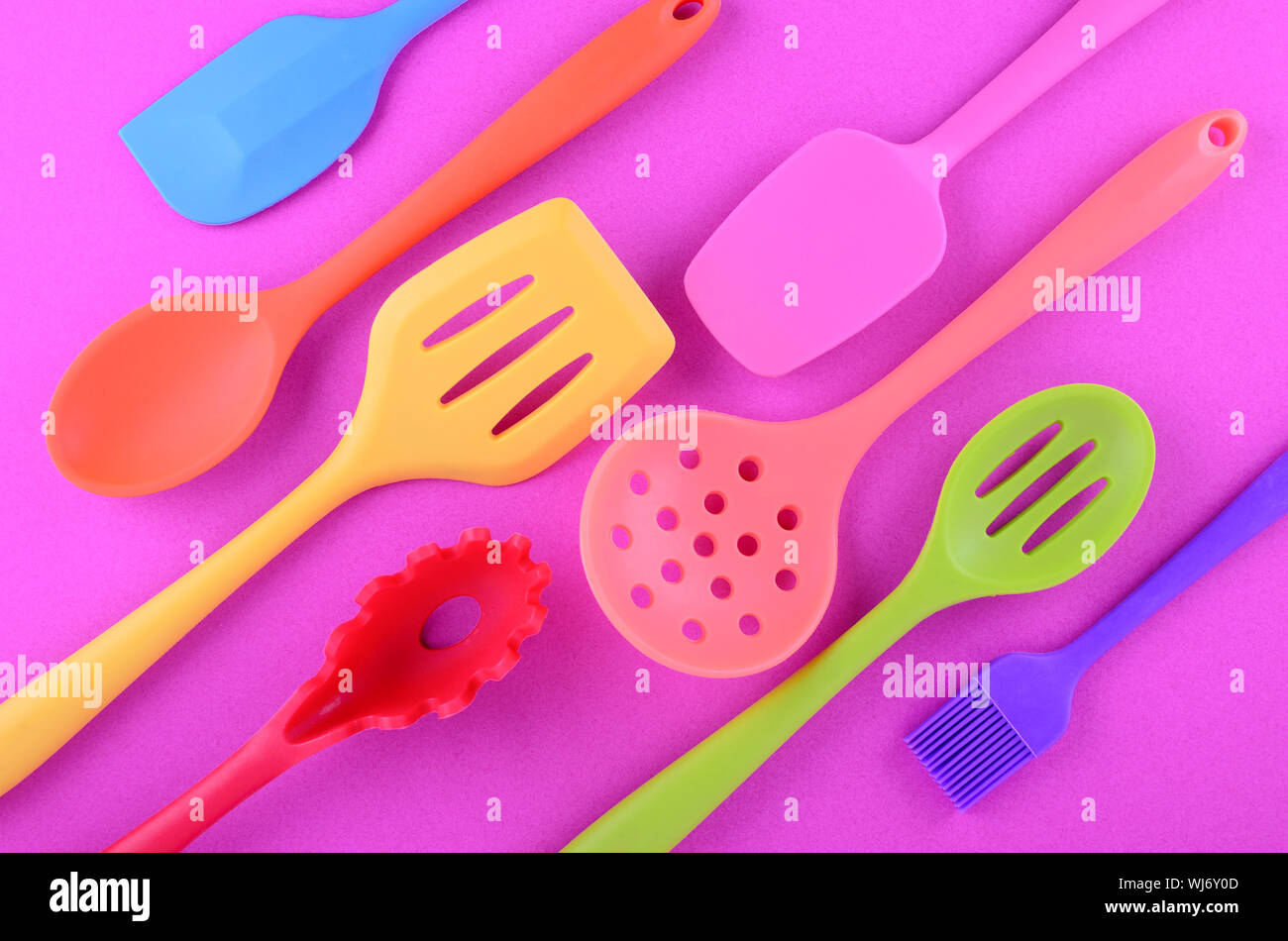 bright multi colored kitchen utensils on purple background Stock Photo