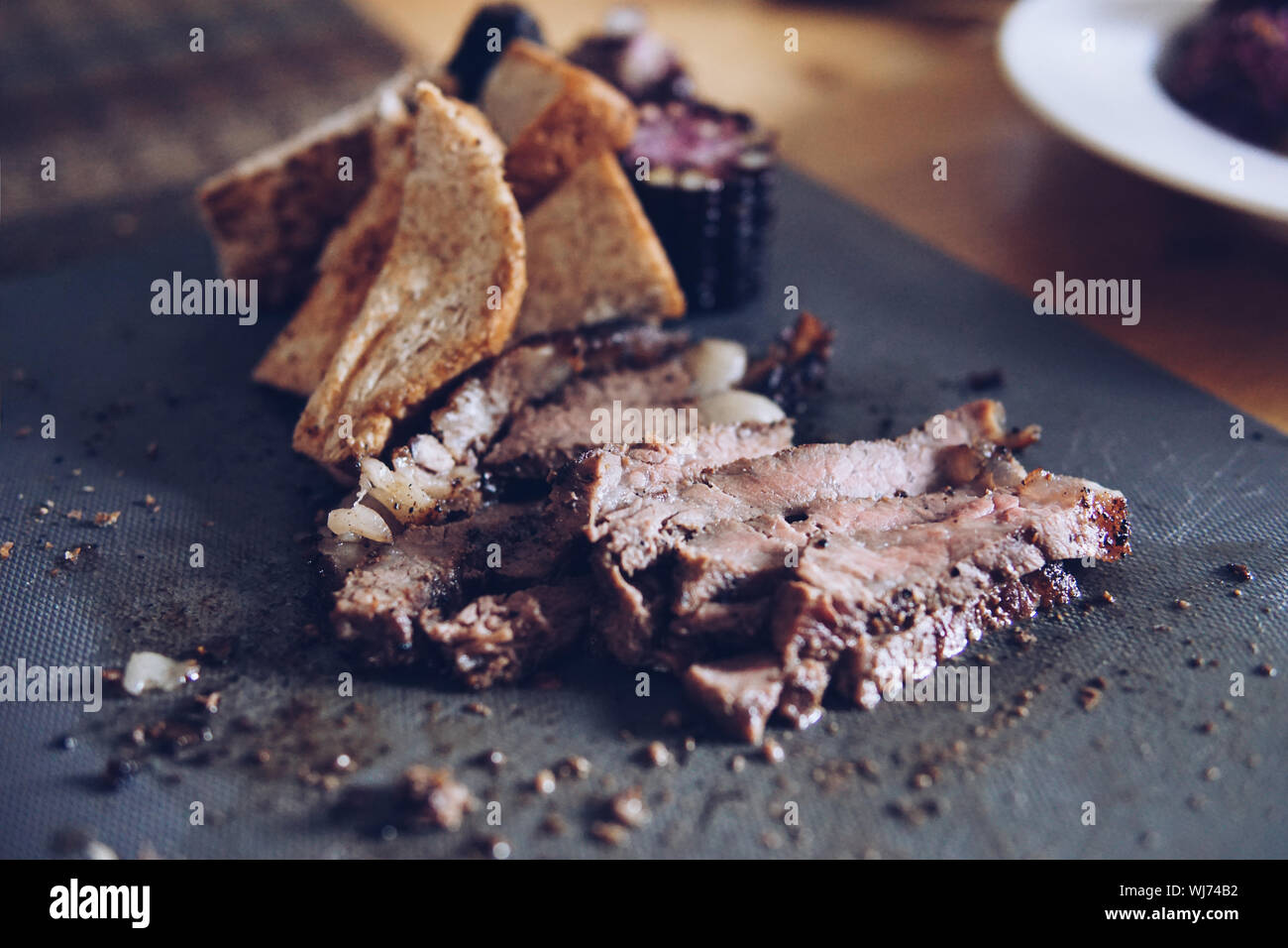 Blurred roast beef, corn, bread served on the table. Stock Photo