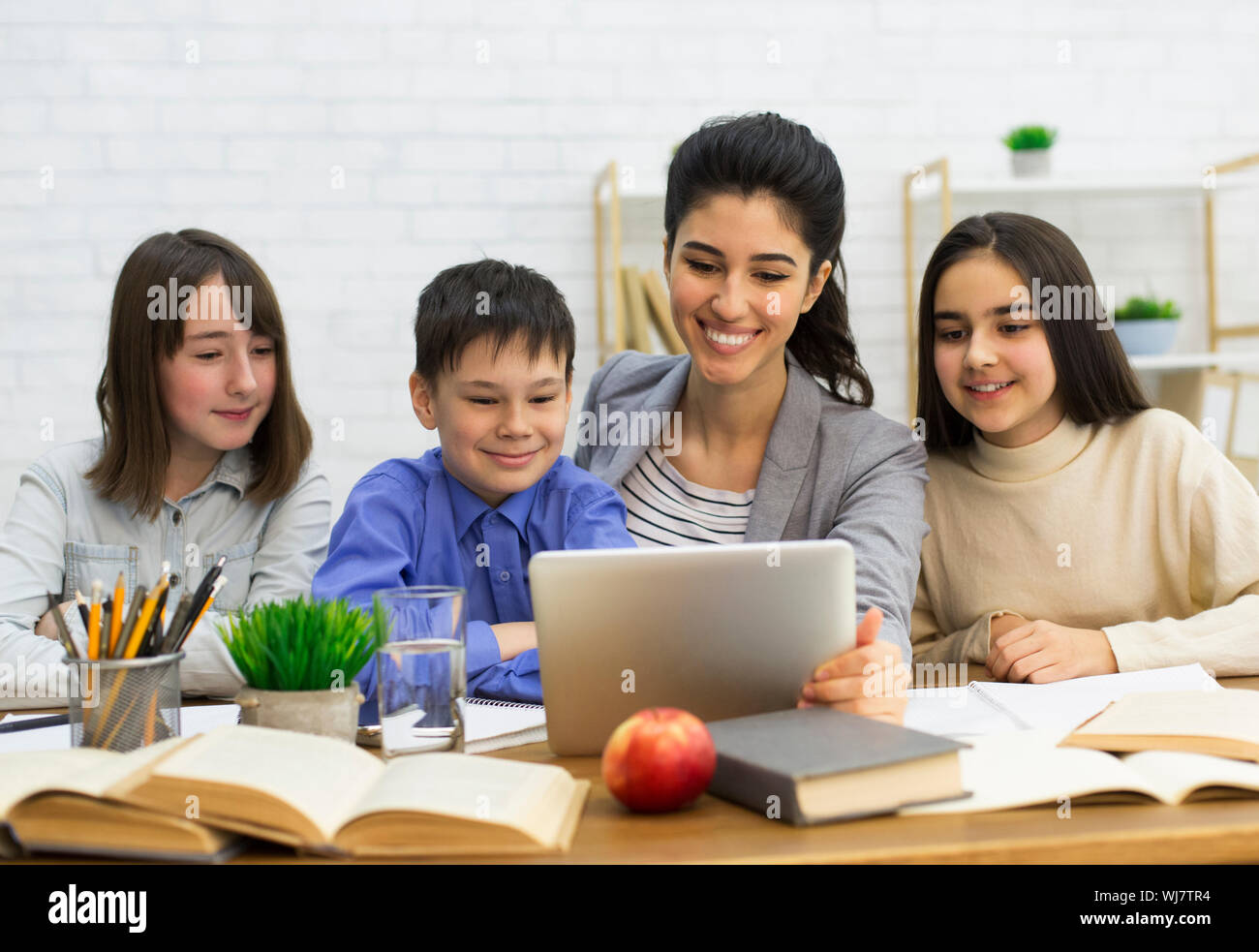 School kids watching videos with teacher on tablet Stock Photo