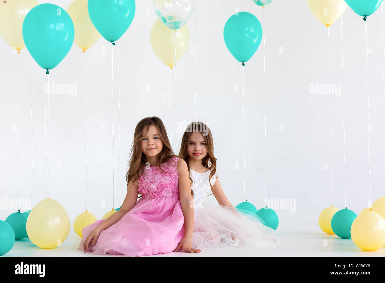 Two sisters on balloons party - isolated over a white background Stock Photo