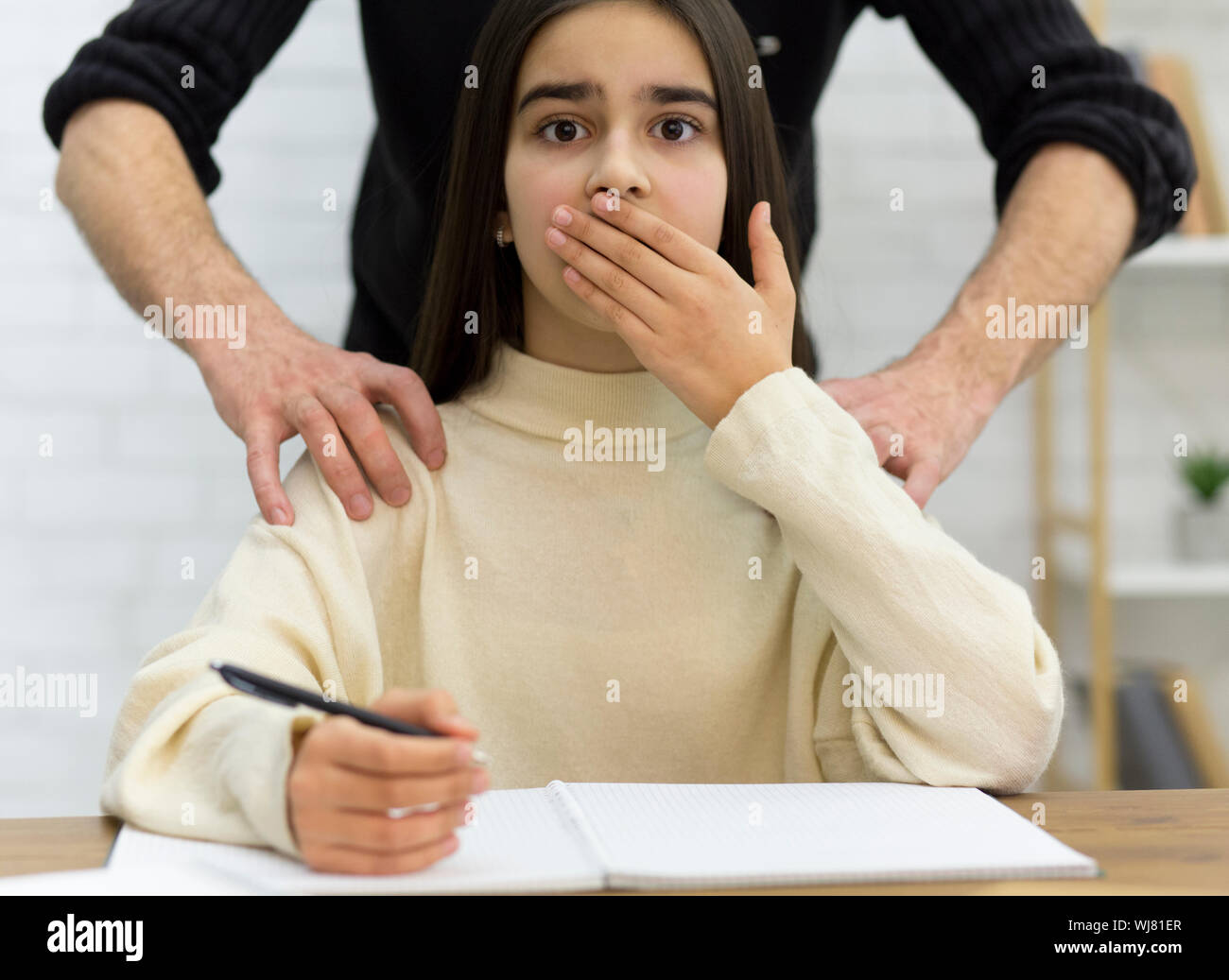 Scared girl victim of pedophilia in school Stock Photo