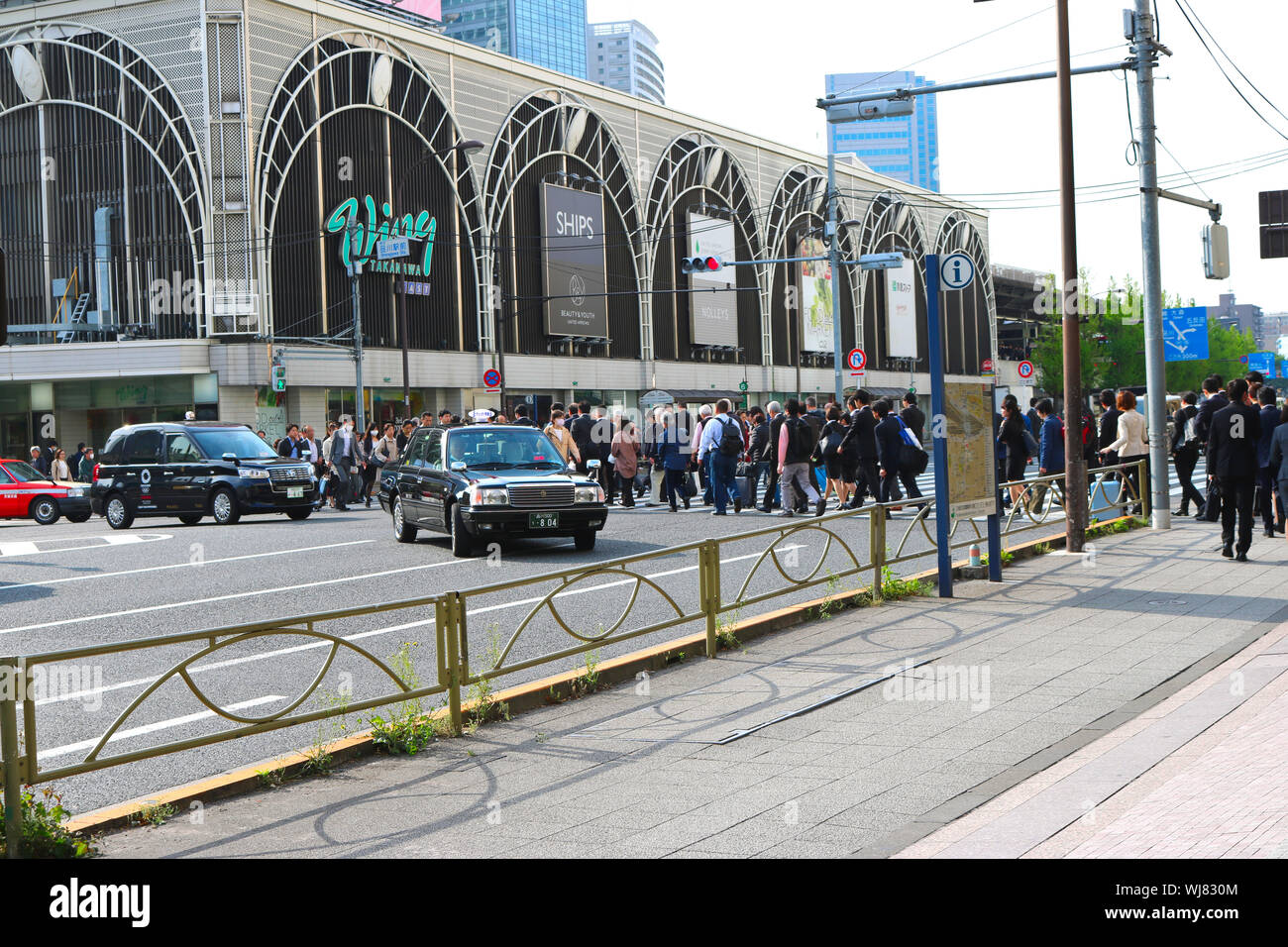 Taxi cars turning right while people from all walks of life crossing