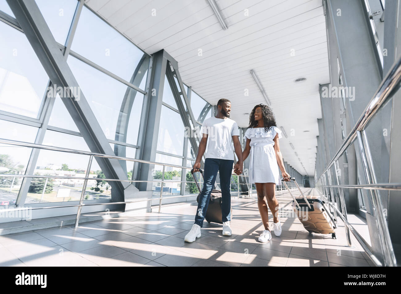African newlyweds walking with suitcases at airport terminal Stock ...