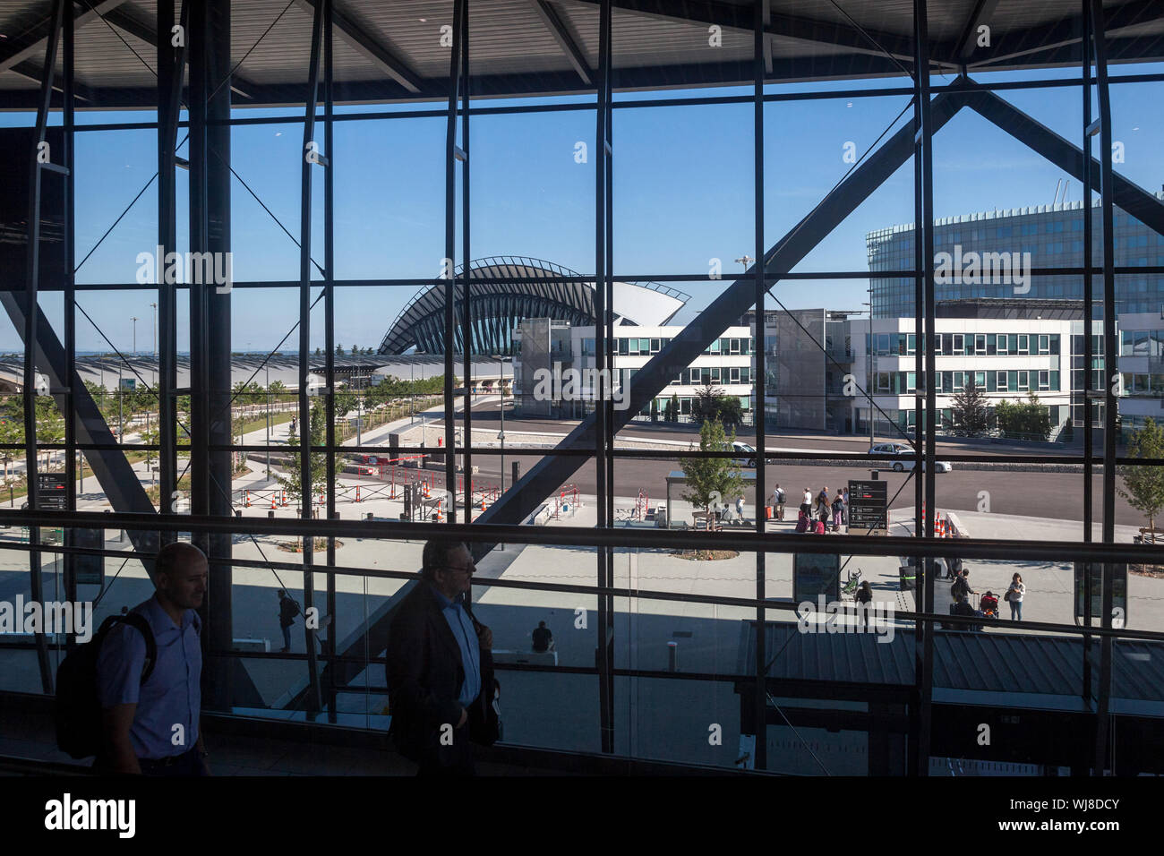LYON, FRANCE - JULY 13, 2019: Passengers passing by the terminal 1 of Aeroport de Lyon Airport, Saint Exupery, while the iconic train station of the a Stock Photo