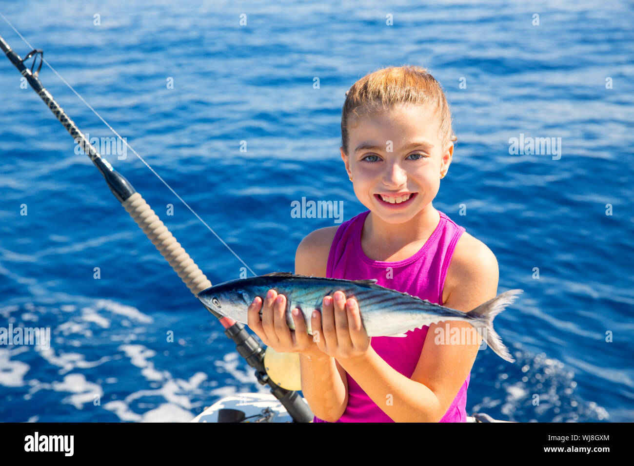 kid girl fishing tuna bonito sarda fish happy with trolling catch on boat deck Stock Photo