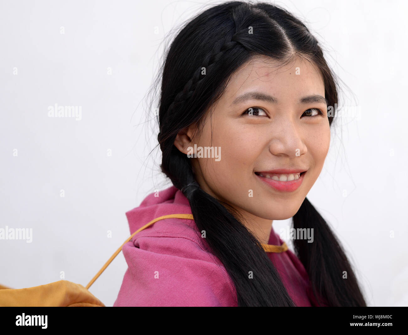 Pretty Thai girl with long pigtails poses for the camera. Stock Photo