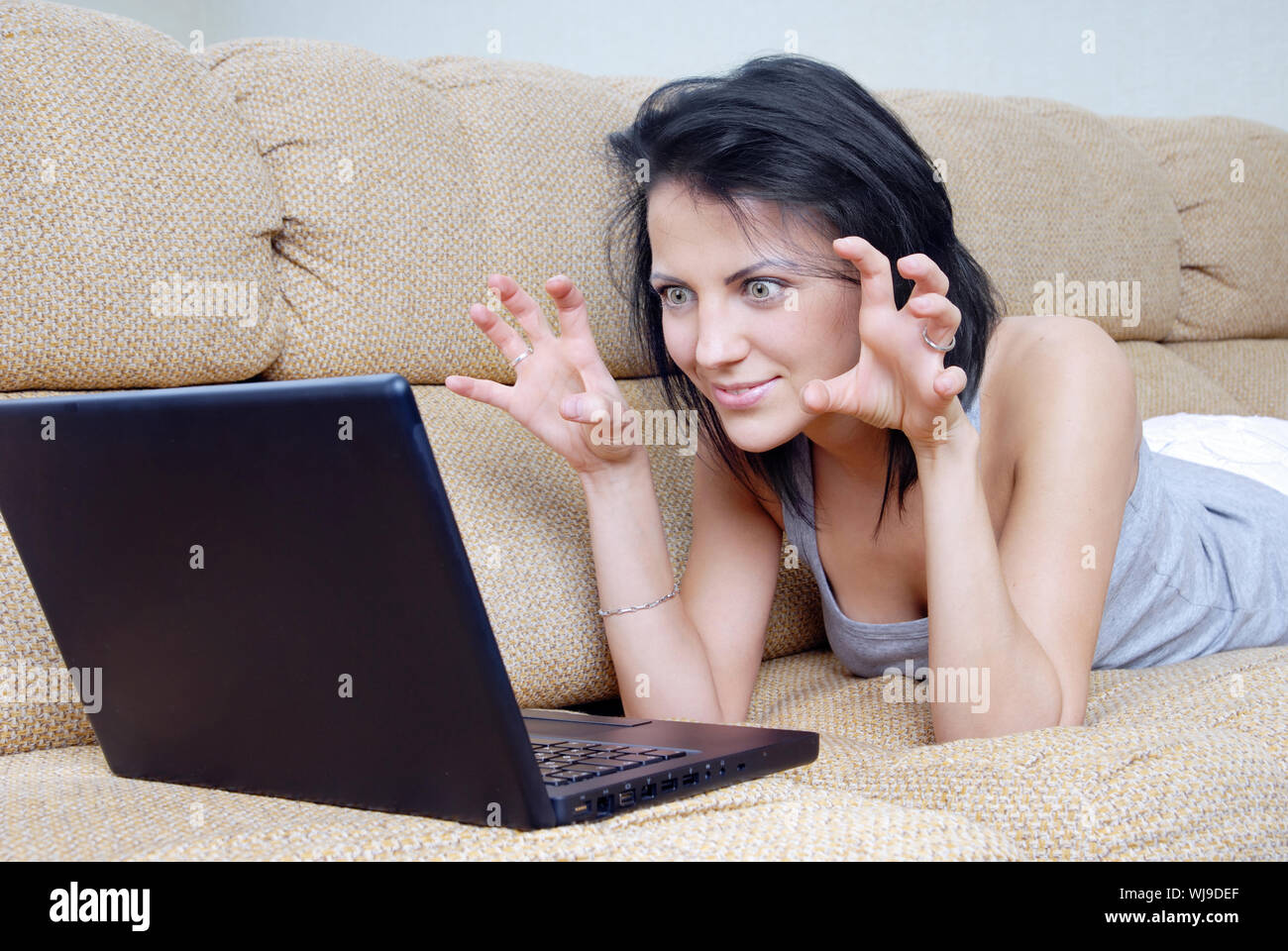 Playful woman laying on a sofe and using wireless laptop Stock Photo