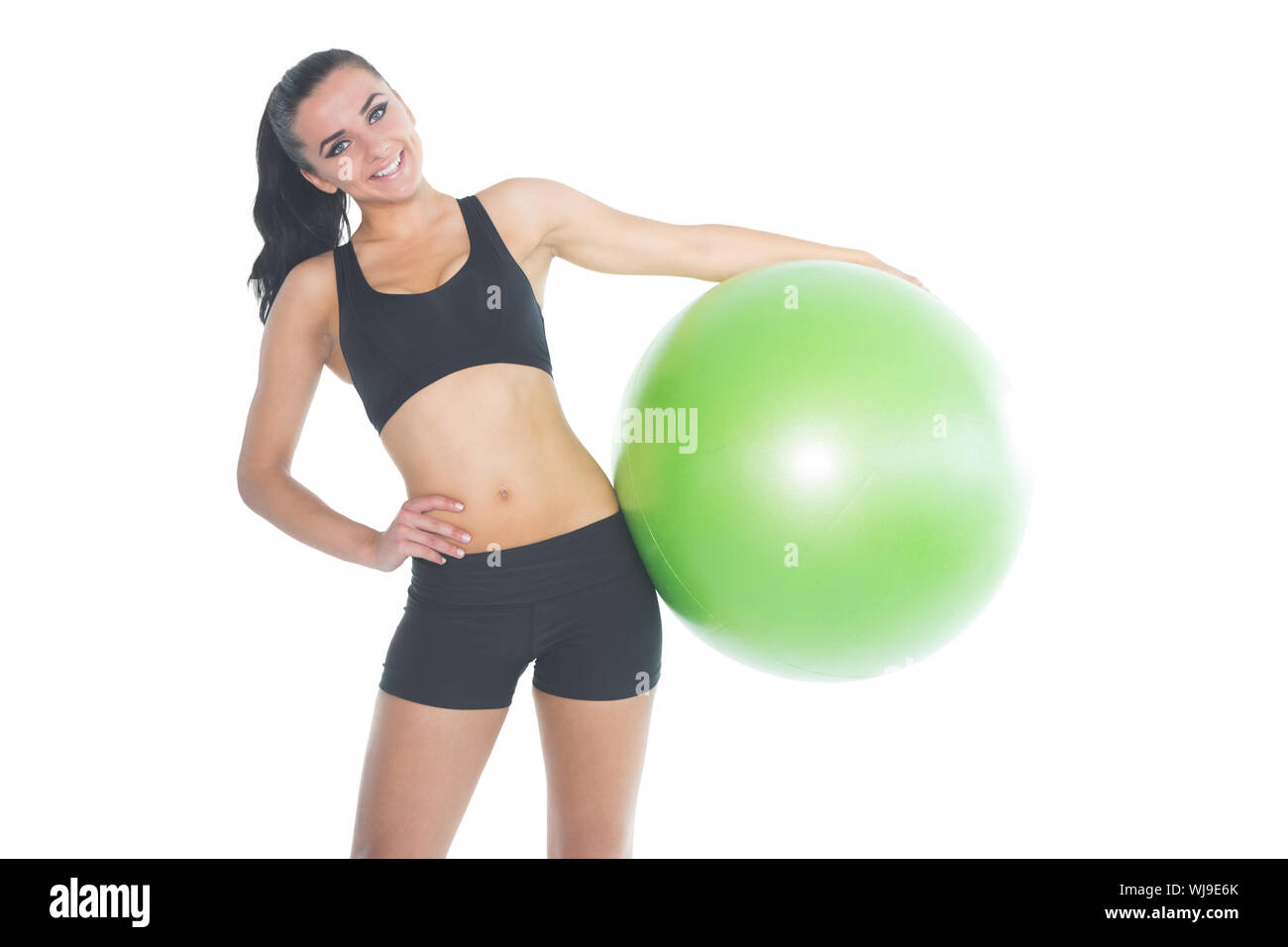 Attractive fit woman posing holding a green exercise ball smiling at camera Stock Photo